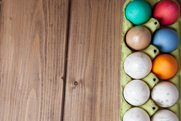 Colorful Easter eggs in box on wooden background with copy space