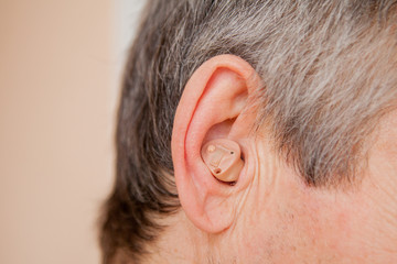 Close-up Digital modern hearing aid in the ear of aged old man
