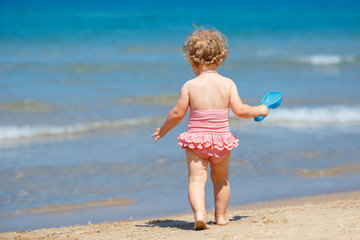 Child playing on tropical beach. Little girl digging sand at sea shore. Kids play with sand toys. Travel with young children