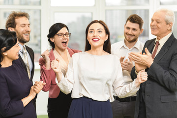 Cheerful businesspeople congratulating their colleague with promotion