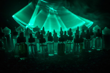 Vape concept. Smoke clouds and vape liquid bottles on dark background. Light effects. Useful as...