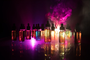 Vape concept. Smoke clouds and vape liquid bottles on dark background. Light effects. Useful as background or electronic cigarette advertisement.