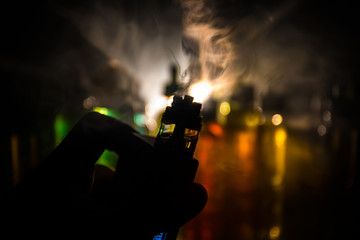 Vape concept. Electronic Cigarette vape explosion. Smoke clouds and vape liquid bottles on dark...