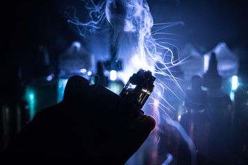 Vape concept. Electronic Cigarette vape explosion. Smoke clouds and vape liquid bottles on dark...