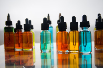 Vape concept. Beautiful colorful vape liquid glass bottles outdoor on stones. Useful as background or electronic cigarette advertisement.