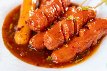 Sausage topped with chili sauce on white background