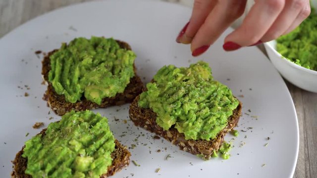 Spreading mashed avocado on toast and sprinkle with salt and spices. Healthy vegan breakfast.