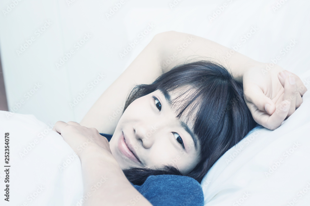 Wall mural asian woman wake up on bed in bedroom in the morning.at home in holiday.