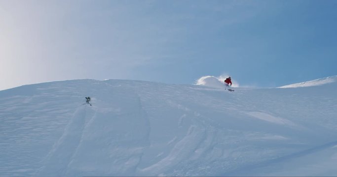 Backcountry skier doing smooth turns in powder on sunny day, amazing ski adventure holiday, slow motion skiing