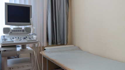 A lying place and a modern medical device in the clinic. Complex ultrasound. Daylight. Copy space. Health research and prevention.