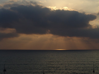 Fototapeta na wymiar Cloudy sunset with light rays over the ocean