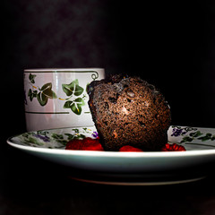A piece of chocolate cake with a mug of a hot beverage.