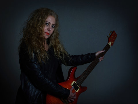 Mujer guitarrista con chaqueta de cuero rockera 