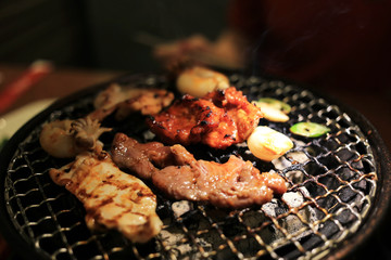 Barbecue meat on grilling mesh of charcoal fire. Korean or japanese traditional food grilling style barbecue.