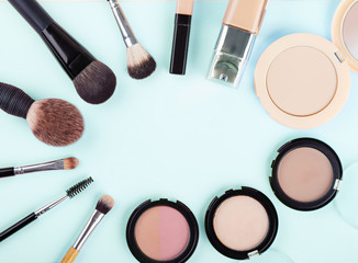 Set of woman's cosmetics on blue background. Women's secrets. Decorative cosmetics: highlighter, concealer, rouge, palette with eye shadows and brushes for face make up, face sculpture . Make up.