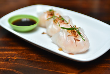 Traditional asian rice dough steamed dumplings with stuffing, spring onion and fried chips decor, served with spicy chilly sauces