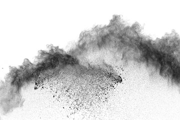 Black powder explosion against white background. Charcoal dust particles exhale in the air.
