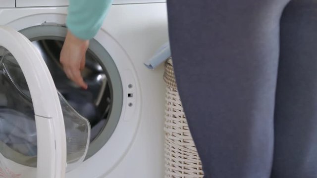 Woman loads the laundry in the washing machine