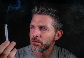 handsome and thoughtful tobacco addict man holding cigarette thinking time to quit smoking isolated on black background in bad habit and addiction concept
