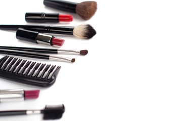 black makeup brushes and lipsticks on white background