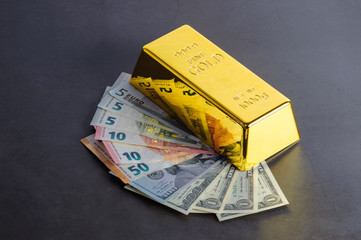 Gold bar ingot bullion against the background of dollar and euro bills.