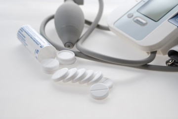 Tonometer - a diagnostic device for determining and monitoring such vital functions of the human body, Antipyretic tablets, painkillers scattered on the table on a white background