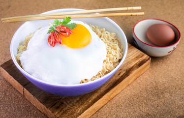Instant noodles serve with egg put on wooden background. Junk food concept, Sodium diet high risk kidney failure.