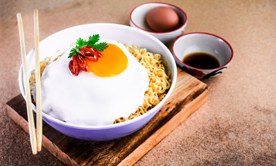 Instant noodles serve with egg put on wooden background. Junk food concept, Sodium diet high risk kidney failure.