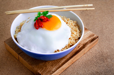 Instant noodles serve with egg put on wooden background. Junk food concept, Sodium diet high risk kidney failure.