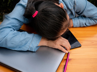 Asian women tired and exhausted from hard work and She slept on the desk with laptop and smart phone in work, working woman concept.