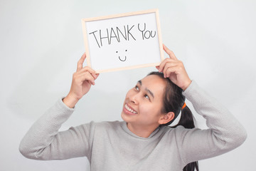 Studio shot of Asian woman holding a Thank you sign writing on whiteboard with handwriting. Isolated on white background.