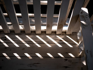 Light from the sun passing through the backrest of a white wooden chair.