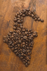 Brown coffee beans in shape of pepper, closeup of macro coffee beans for background and texture. On brown wooden board.