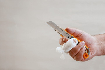 hand with injured finger wrapped with gauze bandage holding knife with copy space