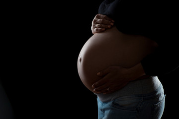 close-up of pregnant belly on a black background