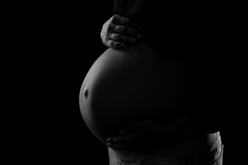 close-up of pregnant belly on a black background