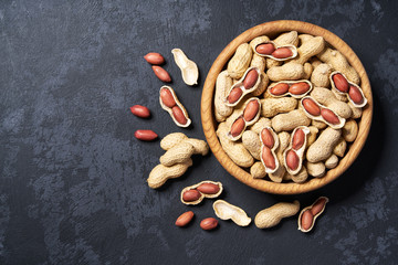 Peanut  in wooden bowl on black background with copy space. Top view