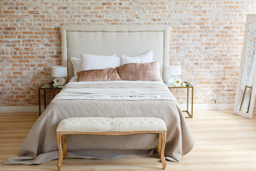 A room in light loft stile with brick wall and light furniture. Comfortable bedroom. A combination of modern and old. Join the glass and brick. Modern lamp on a glass bedside table. 