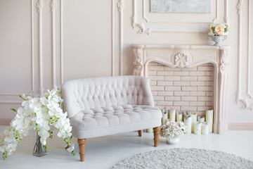 Elegant soft arm-chair near a fireplace. Luxury interior in white colors. Armchair with fabric upholstery
