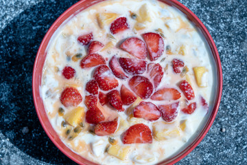 Mango, passion fruit, strawberry and yogurt brulee. Fruit dessert on breakfast with wedges of perfectly ripe in season mangoes and strawberry, covered fresh passion fruit pulp