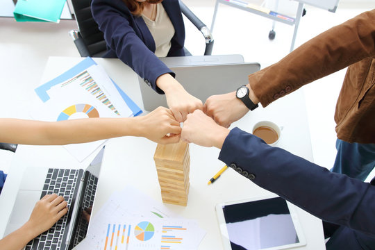 Hands of young business people giving fist bump together to greeting complete dealing in office. Success and teamwork concept.