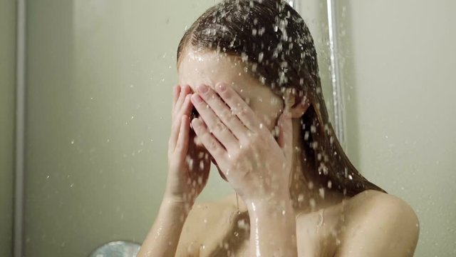 Young beautiful woman taking a shower in a bathroom. Slow motion. HD