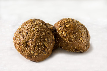 Twee round dark colored buns with varios seeds on a light background. Close up. Buns for a breakfast, filling, dessert