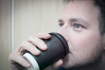 A man at work looking bored while drinking his morning coffee