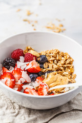 Granola with milk, chia, berries and peanut butter in a white bowl.