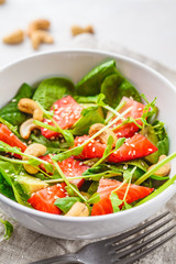 Summer strawberry avocado salad with cashews in a white bowl.