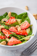 Summer strawberry avocado salad with cashews in a white bowl.