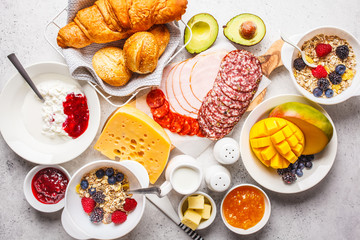 Continental breakfast table with croissants, jam, ham, cheese,  butter, granola and fruit.
