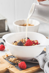 Breakfast food background. Granola with milk and berries on white table.