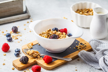Breakfast food background. Granola with milk and berries on white table.
